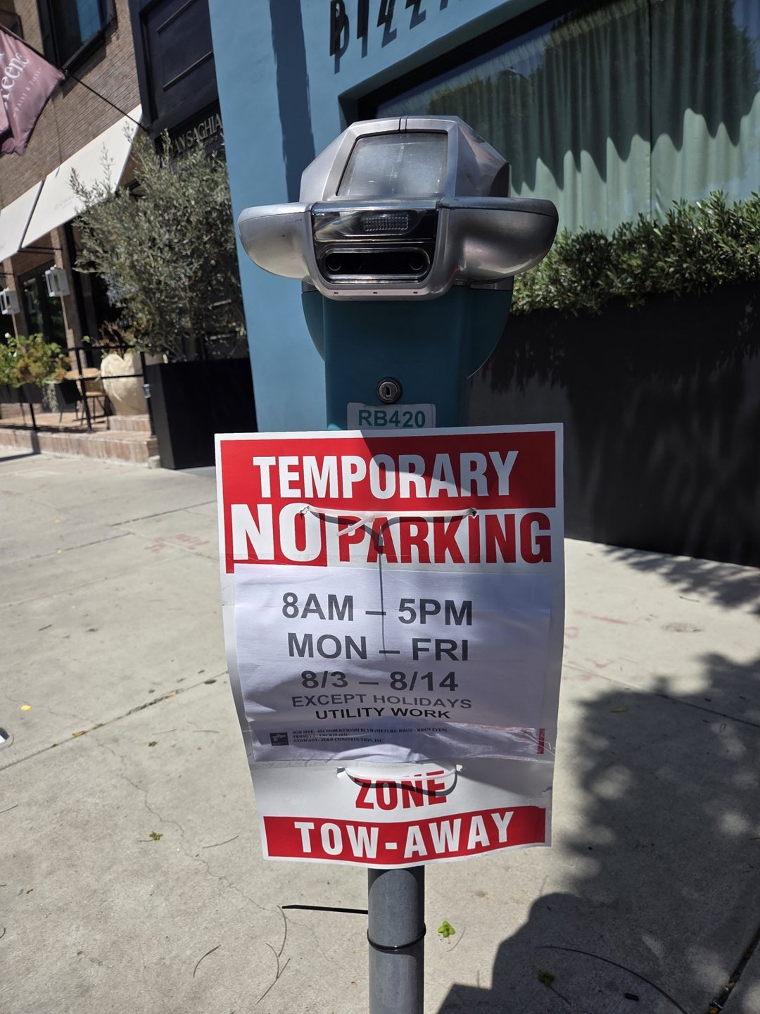 Red-and-white temporary no-parking sign posted on a parking meter along the sidewalk at 454 N Robertson Blvd.